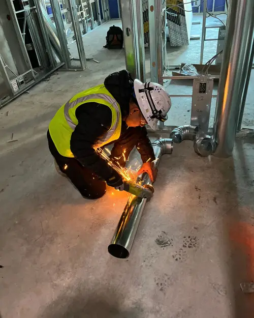 Crew member cutting pipe on a construction site