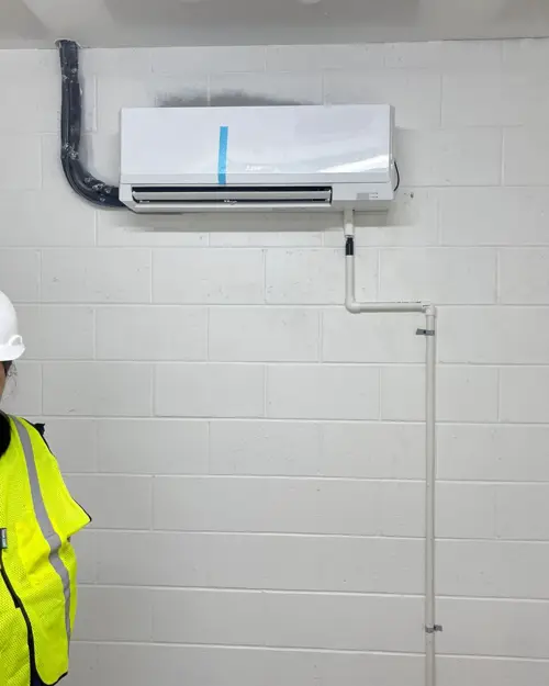Technician in a hard hat beside a new mini-split