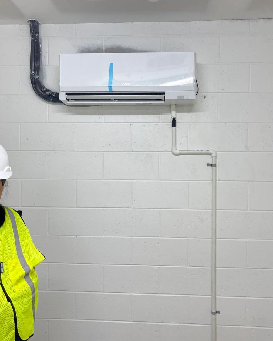 Technician beside a newly installed mini-split in an apartment